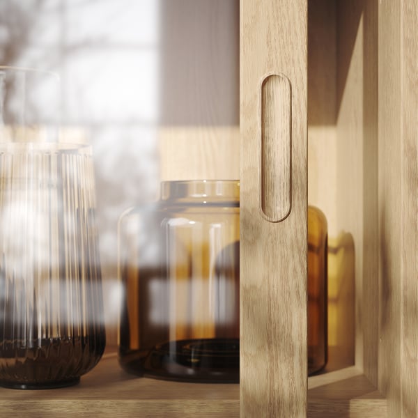Minimalistiskt träskåp med burkar i klart glas, mjuk belysning och räfflade handtag.