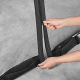 En person håller på att stänga ett insektsnät från Torpön, som fästs i ett parasoll, vilket skapar ett förseglat, insektsfritt utrymme.