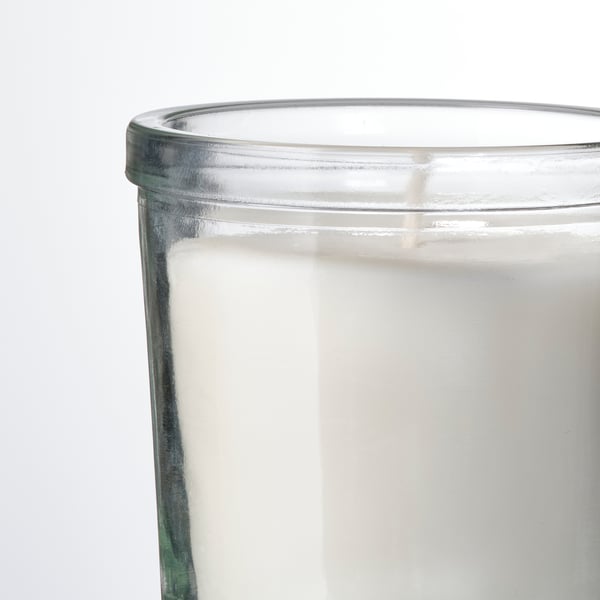 Ett genomskinligt glasljus med en vit etikett och synligt vitt vax.