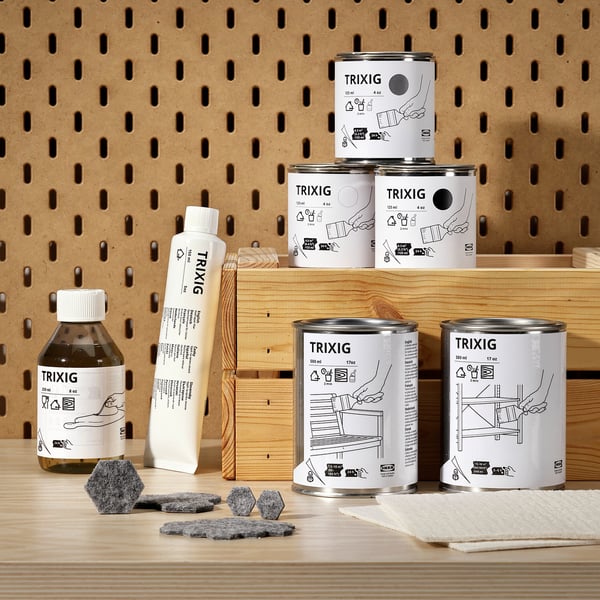 TRIXIG växtoljeprodukter: brun flaska, vit tub, svarta burkar, serveringsbräda, svampar, pärlplatta.