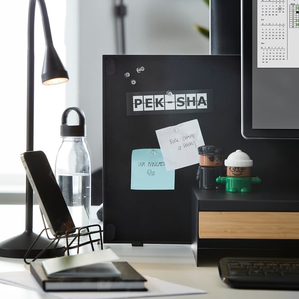 Kontorsinställning: skrivbord, dator, lampa, telefonhållare, vattenflaska, anteckningar, kalender, pennkopp, tangentbord.