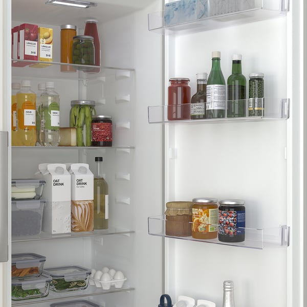 Organiserat kylskåp med tydliga hyllor som visar olika livsmedel, inklusive frukt, grönsaker, drycker och mejeriprodukter. En skarpare låda är synlig.