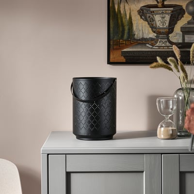 Dekorativ lykta med intrikat design på skänken, omgiven av timglas, torkade blommor och inramad konst.