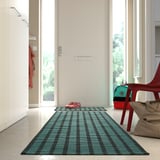 Blågrön och svartrandig matta nära dörren, bredvid den röda stolen.