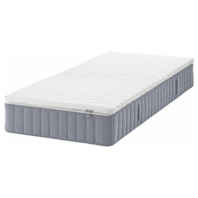 En IKEA VALEVÅG pocketresårmadrass i vitt, insvept i ett grått överdrag, designad för fastare komfort och andningsförmåga.