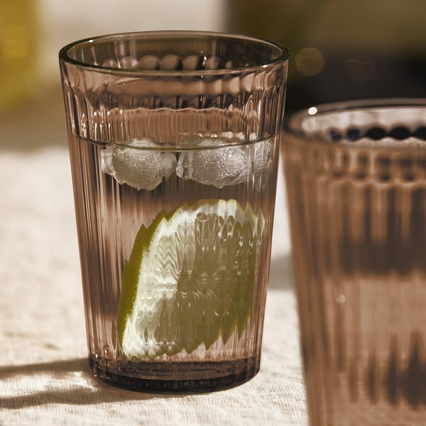 Två höga, rejäla glas med räfflad design, innehållande is- och citronskivor, perfekta för servering av kylda drycker.