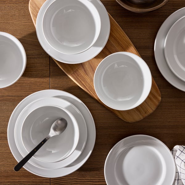 Vita VARDAGEN-porslinstallrikar och skålar på träbord, klassisk design, metallsked.