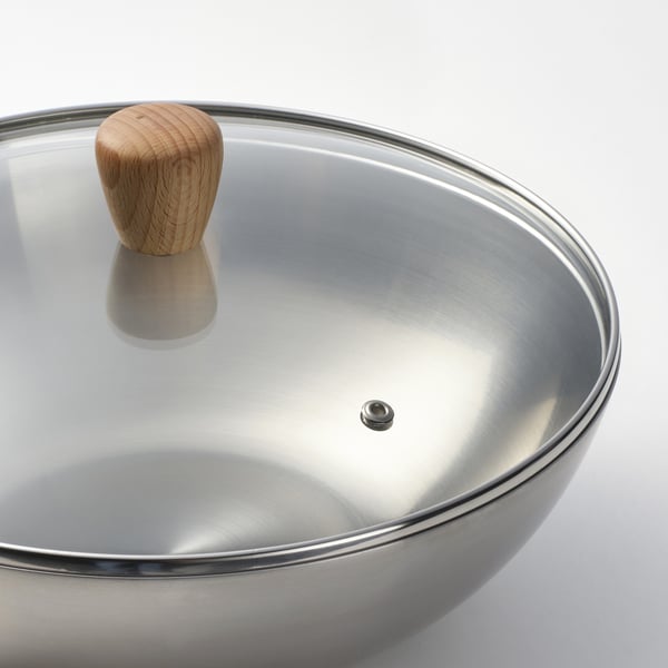 En högkvalitativ wok i rostfritt stål med en elegant, reflekterande yta och ett robust trähandtag, perfekt för matlagning.