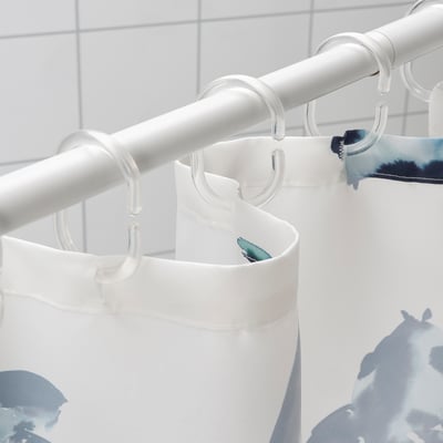 Klar duschdraperistång som håller vit och blå gardin med fiskdesign.