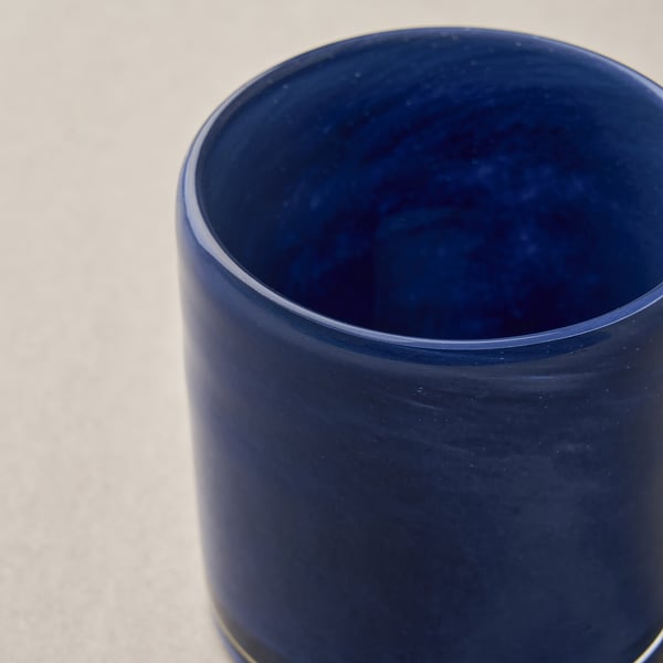 Marinblå glasvas på vit yta, slät och utformad.