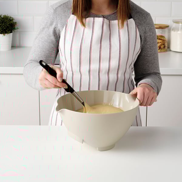 En person blandar smet i en lutande, ergonomisk VISPNING-blandningsskål med en handtagspip i ett ljust kök.