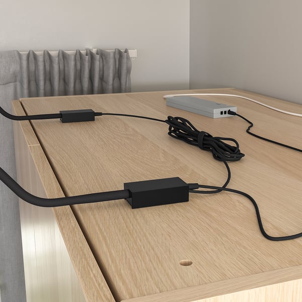 En tunn, justerbar lampa monterad på ett träskåp, med en flexibel hals som riktar mjukt ljus nedåt.