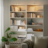 Mysigt vardagsrum med bokhylla, växt, kamera och soffa. Väl upplyst av YTBERG-lampor.