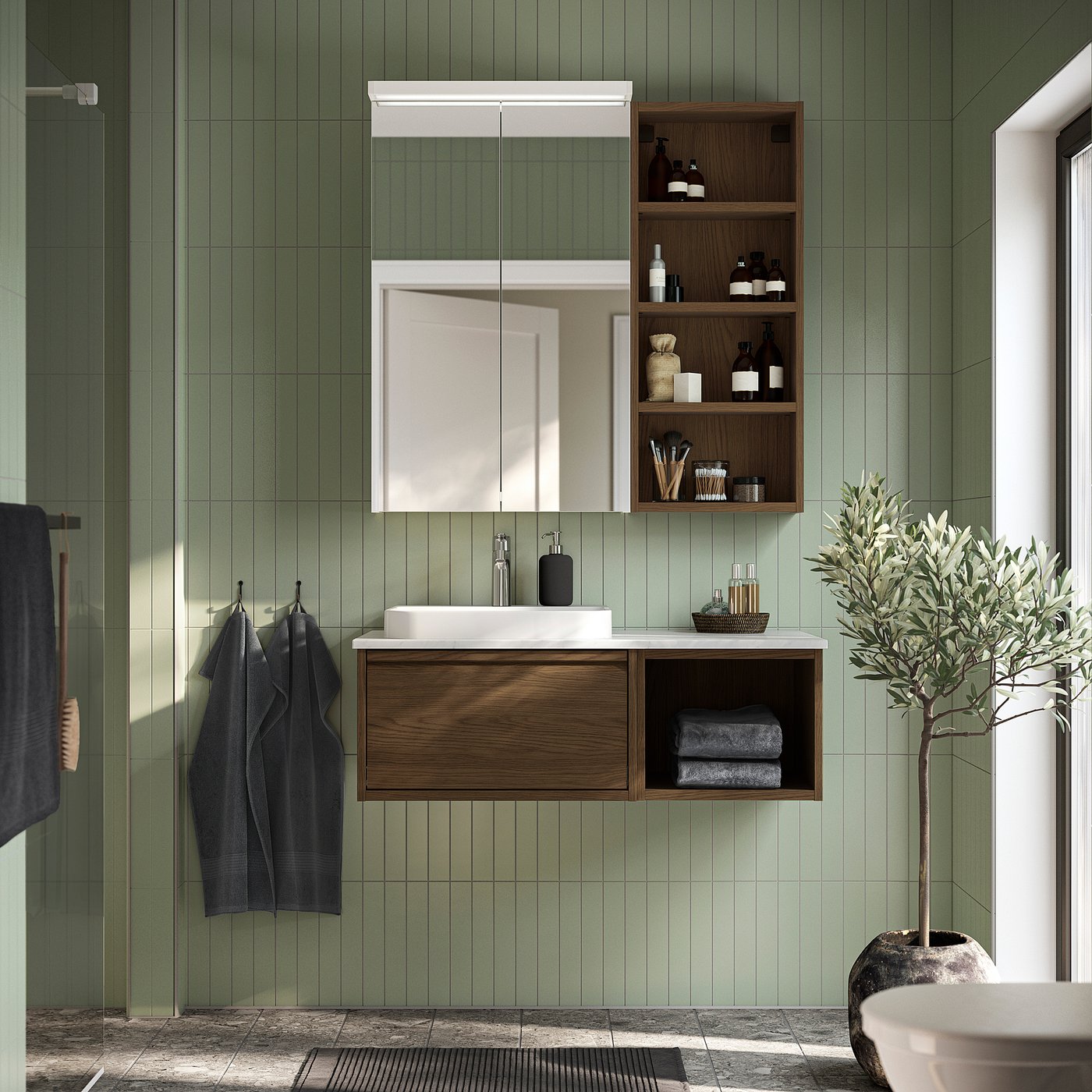 Salle de bain moderne avec meuble-lavabo ÄNGSJÖN en chêne brun, vasque en marbre et rangements ouverts. L’armoire de toilette et l’olivier rehaussent l’aspect élégant et organisé.