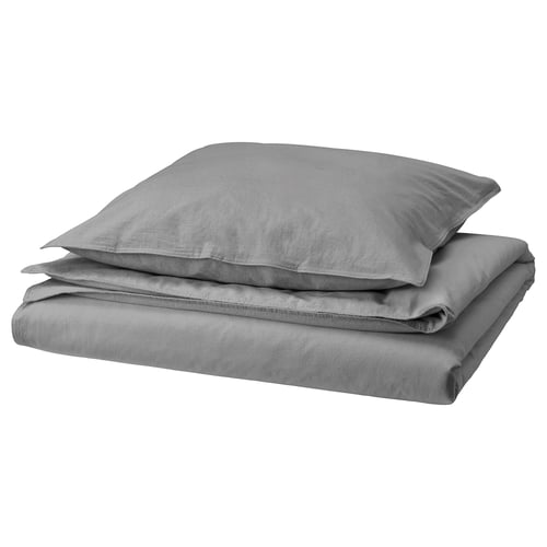 Ensemble de literie en lin gris comprenant housse de couette et taies d’oreiller en pile soignée sur fond blanc.