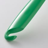 Brosse à vaisselle verte avec poignée incurvée et poils, conçue pour enlever les débris alimentaires, se suspend pour le séchage.