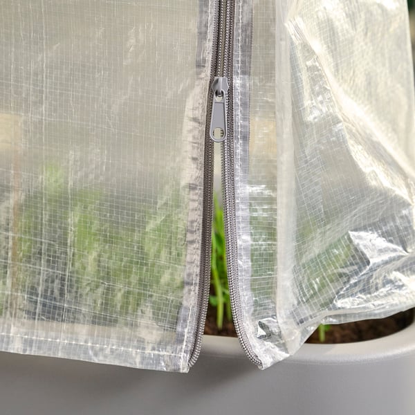 Une couverture de serre, blanche, en polyéthylène, avec des fermetures éclair pour l’accès. Il protège les plantes des intempéries.