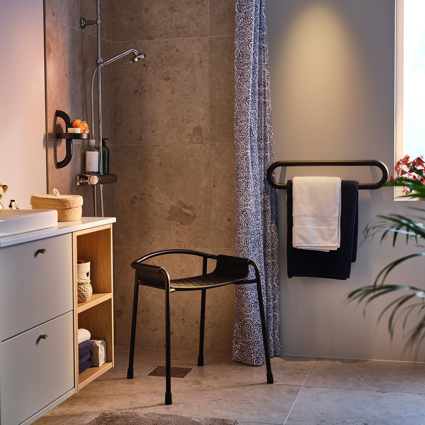 Salle de bains moderne avec étagère de douche gris foncé BÄSINGEN, porte-serviettes suspendu, meuble lavabo blanc et rideau de douche à motifs.