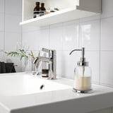 Distributeur de savon BALUNGEN chromé sur évier blanc avec robinet chromé et verdure.