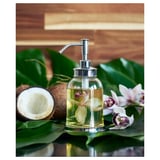 Distributeur de savon chromé chic avec des fleurs jaunes sur une surface en bois.