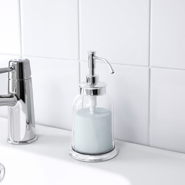 Le distributeur de savon chromé maintient le savon liquide bleu sur un comptoir blanc.