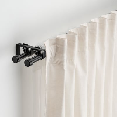 Ensemble de tringle à rideau noir avec rideaux blancs, supports et embouts fixés au mur.