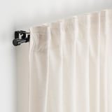 Gros plan sur l’ensemble de tringles à rideaux BEKRÄFTA. Tringle et faîteau noirs fixés au mur à l’aide de supports, tenant des rideaux de couleur claire.