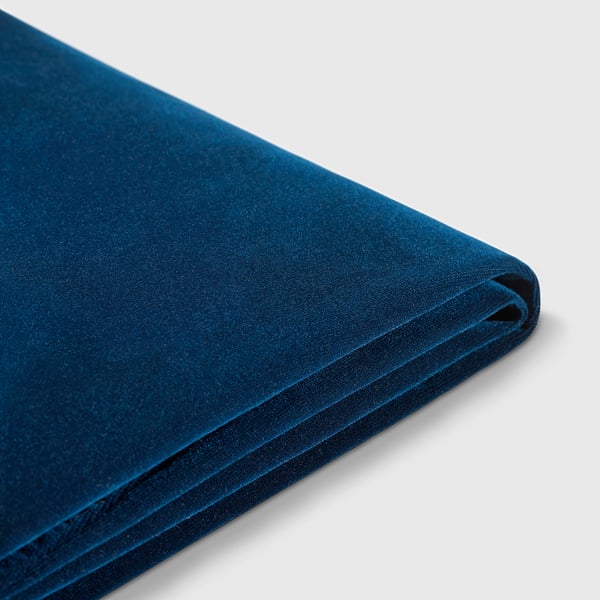 Couverture en velours bleu profond, texture lisse, pliée soigneusement, qualité élégante.