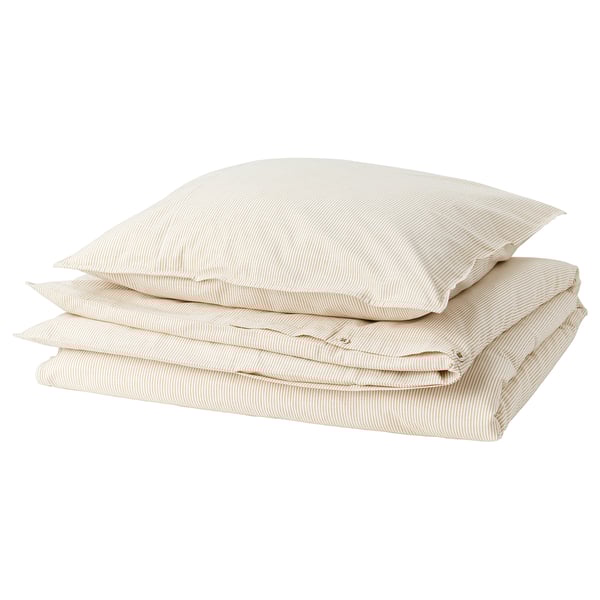 Une housse de couette BERGPALM beige pliée avec des rayures blanches sur fond blanc. L’ensemble comprend une housse de couette et des taies d’oreiller.