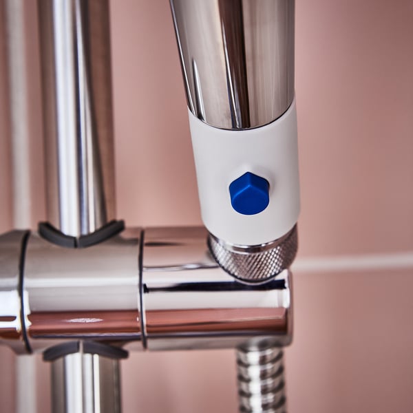 Rehausseur de douche en métal poli et corps blanc, bouton bleu ; assure un écoulement efficace de l’eau.