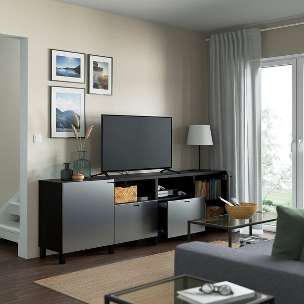 Salon avec banc tv BESTÅ, rangement, gestion des câbles, étagères réglables, photos, lampe, table basse, fenêtre avec rideaux.