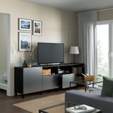 Salon avec banc tv BESTÅ, rangement, gestion des câbles, étagères réglables, photos, lampe, table basse, fenêtre avec rideaux.
