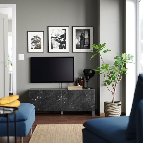 Salon moderne avec banc de télévision BESTÅ, sièges bleus, art mural et plante.