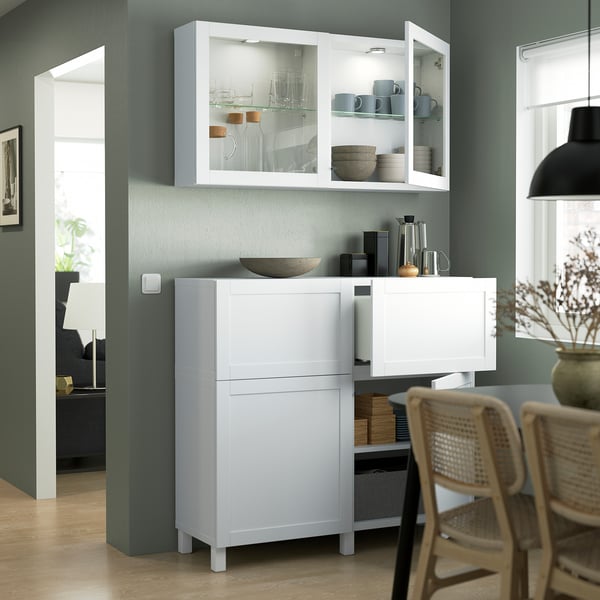 Salle à manger moderne : armoire blanche avec chaises en verre et en osier autour de la table.