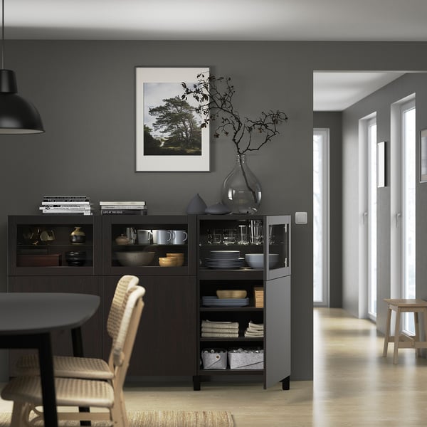 Salle à manger moderne avec buffet sombre, tasses, bols, serviettes et décoration.