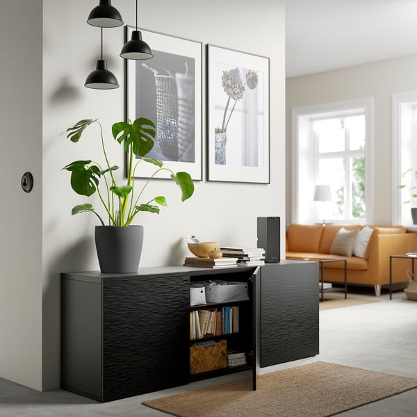 Salon moderne avec rangement BESTÅ, plante, livres, canapé orange, vue.