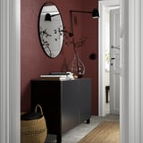 Entrée moderne : buffet BESTÅ, miroir, lumière, panier. Des livres, des fleurs, un mur rouge.