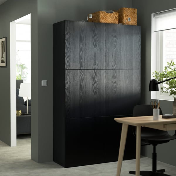 Armoire BESTÅ gris foncé à quatre portes, associée à un bureau et une chaise dans un cadre moderne.