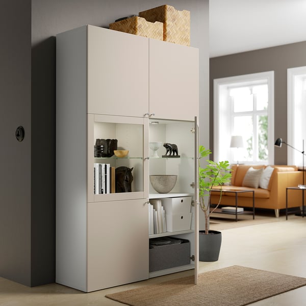 Salon moderne avec unité de rangement BESTÅ, portes vitrées et rangements cachés.