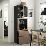 Une salle à manger moderne, une grande armoire BESTÅ avec des portes vitrées, des tasses et des bols, et des tiroirs en dessous pour un rangement caché.