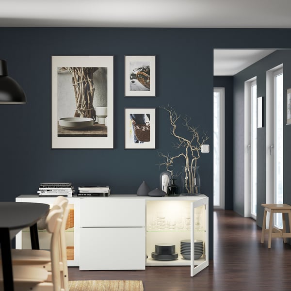 Salle à manger avec des murs bleu foncé, des meubles blancs, de la décoration et des photos.