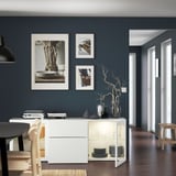 Salle à manger avec des murs bleu foncé, des meubles blancs, de la décoration et des photos.