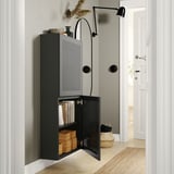 Unité de rangement murale BESTÅ noire avec porte ouverte révélant des livres et des boîtes. Charnières réglables, design moderne.