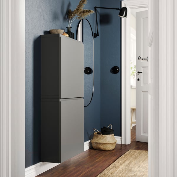 Couloir moderne avec paroi bleue, unité de rangement BESTÅ noir et gris, panier en osier, applique murale noire.