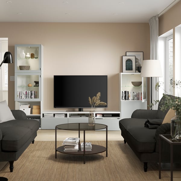 Salon moderne un meuble de rangement tv BESTÅ avec étagères réglables, câbles cachés. Des tiroirs à fermeture douce et une table basse en verre avec des magazines.
