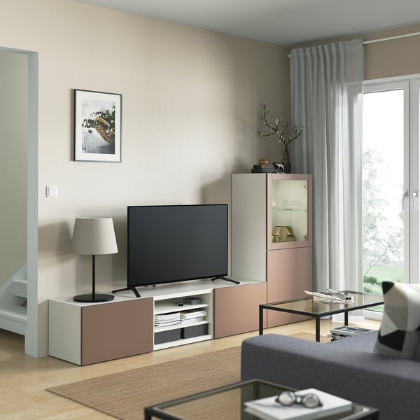 Salon moderne avec rangement TV BESTÅ, écran plat, étagères, tiroirs, armoire en verre, lampe, vase, art et rideaux de fenêtre.