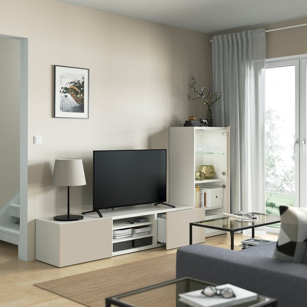 Salon moderne avec meuble TV BESTÅ, écran plat, étagères réglables, table basse en verre, lampe et photo encadrée.