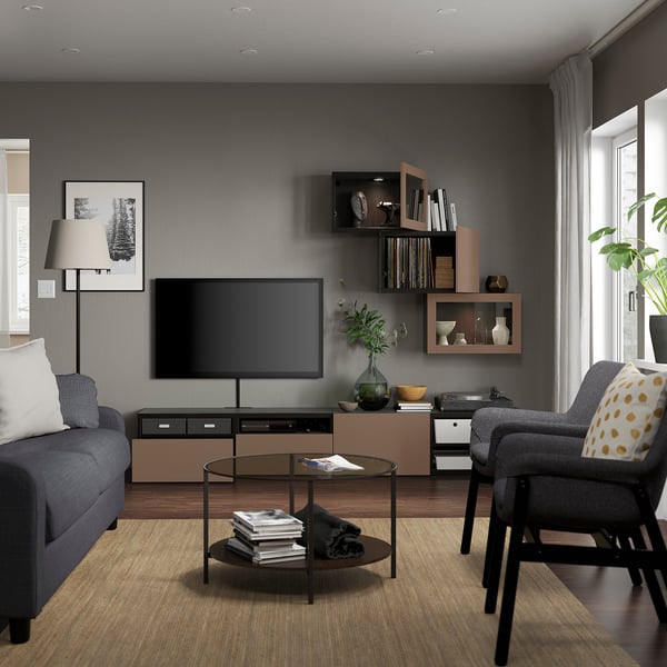 Salon moderne avec canapé gris, table basse en verre, télévision sur pied, étagères avec décor et grande fenêtre.