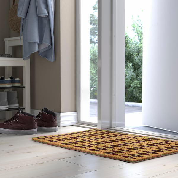 Tapis BETALVÄG marron et noir près d’un porte-chaussures avec manteau.