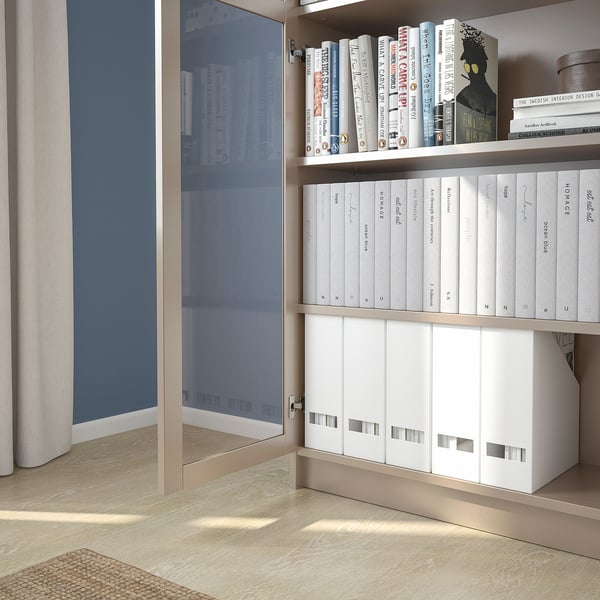 Bibliothèque avec portes vitrées, mettant en valeur les livres et les boîtes de rangement. Les étagères sont réglables.